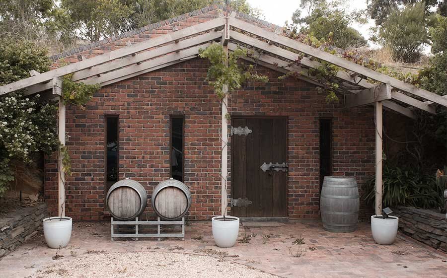The brick cellar built into the hillside beside the homestead, with barrels at the door