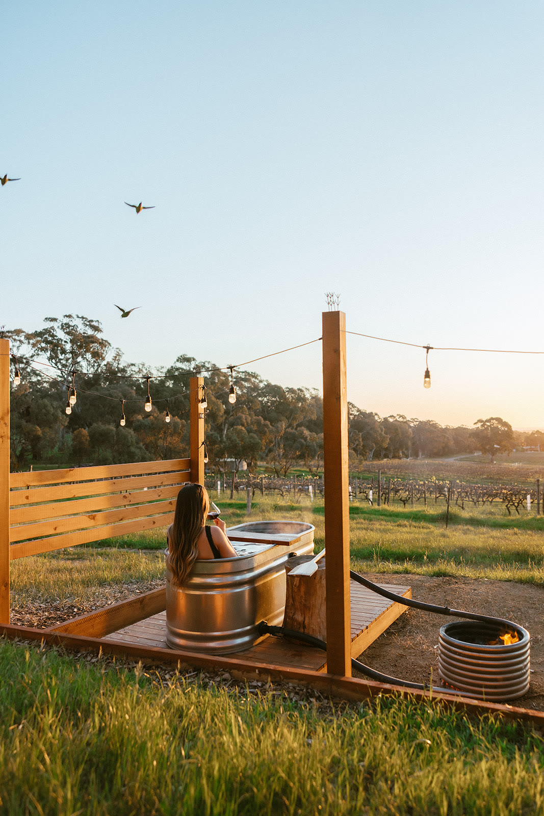 An outdoor bath on the deck of a Monapilla Escape villa, looking over the farm at dusk