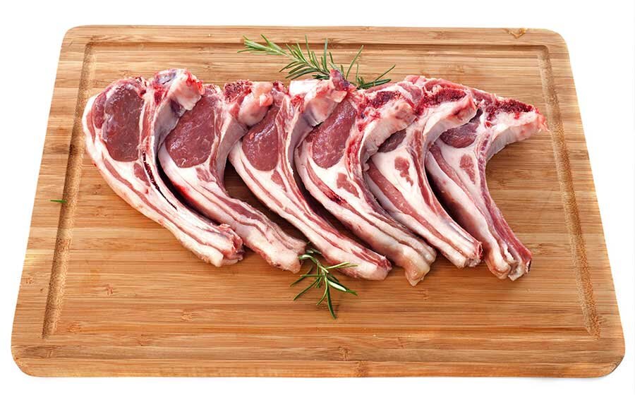 A rack of Monapilla Suffolk lamb cutlets on a timber board with rosemary
